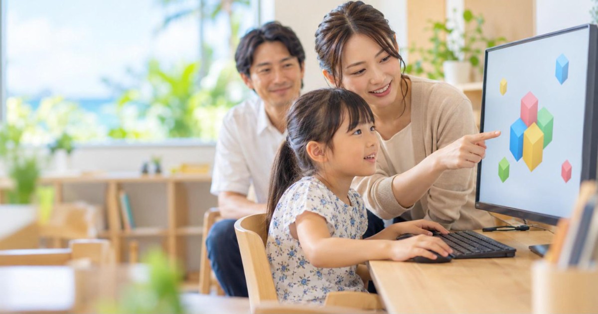 体験授業で講師に教わる女の子と、後ろで見守る父親